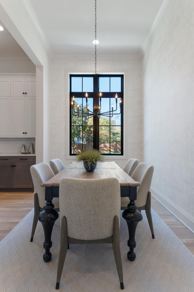 dining area with light hardwood / wood-style flooring, crown molding, and a notable chandelier