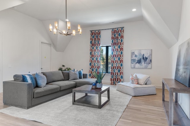 living room with a chandelier, lofted ceiling, and light hardwood / wood-style floors