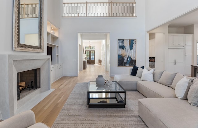 living room featuring a towering ceiling, built in features, and light hardwood / wood-style flooring