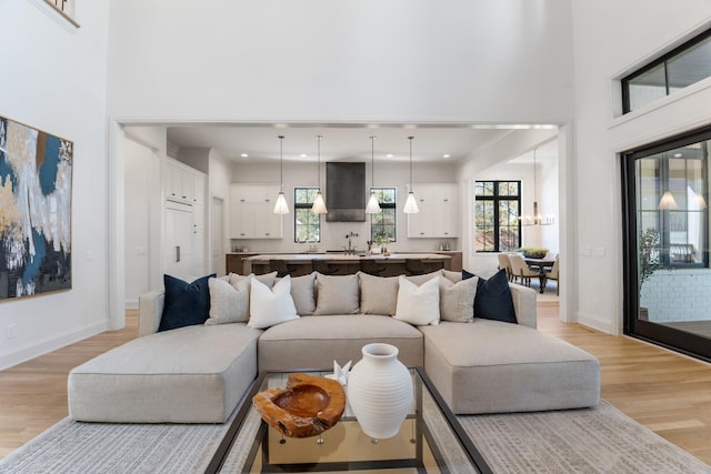 living room featuring light wood-type flooring and a towering ceiling