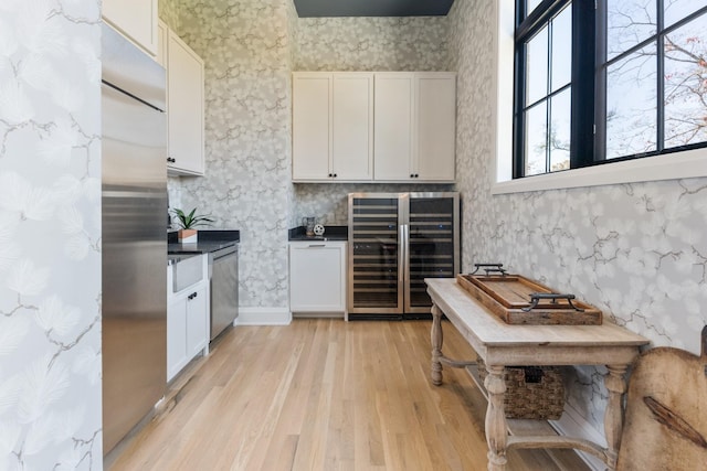 kitchen featuring white cabinets, light hardwood / wood-style flooring, stainless steel appliances, and wine cooler