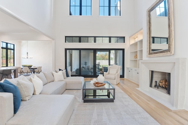 living room featuring built in shelves, a healthy amount of sunlight, a towering ceiling, and a fireplace