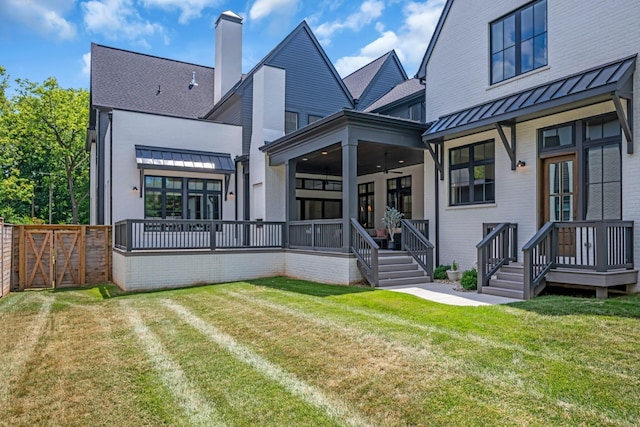 rear view of property with ceiling fan and a yard