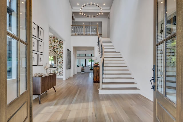 foyer featuring a towering ceiling, an inviting chandelier, and light hardwood / wood-style floors