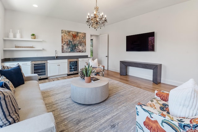 living room with wine cooler, a notable chandelier, and light hardwood / wood-style floors