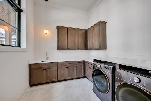 clothes washing area featuring sink, washer and dryer, crown molding, and cabinets