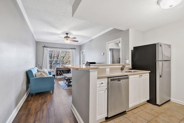 kitchen with ceiling fan, stainless steel appliances, a textured ceiling, white cabinets, and sink