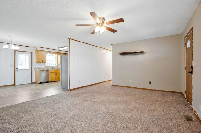 unfurnished living room featuring light carpet, ceiling fan with notable chandelier, and a textured ceiling