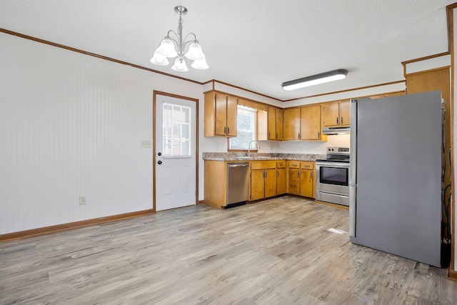 kitchen featuring pendant lighting, ornamental molding, appliances with stainless steel finishes, and sink