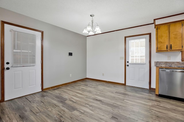 unfurnished dining area with crown molding, a textured ceiling, light hardwood / wood-style floors, and a chandelier