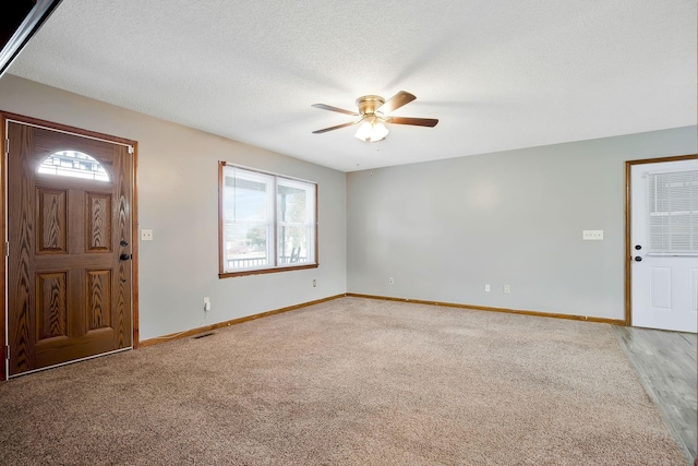 carpeted entrance foyer featuring ceiling fan and a textured ceiling