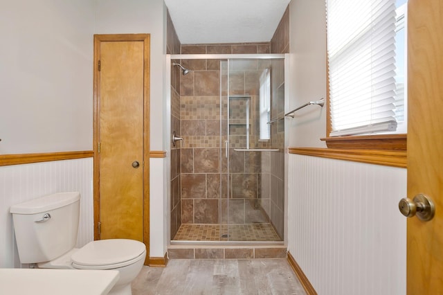 bathroom with a shower with shower door and toilet