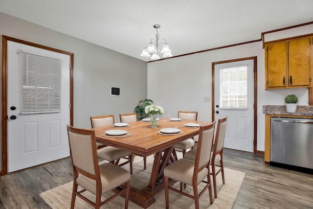 dining room featuring an inviting chandelier, ornamental molding, light hardwood / wood-style floors, and a textured ceiling