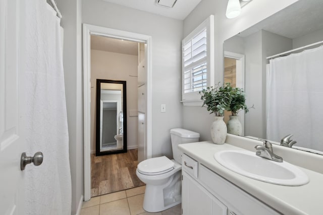 bathroom with toilet, vanity, and tile patterned flooring