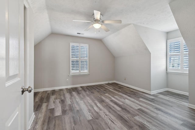 additional living space featuring ceiling fan, vaulted ceiling, a textured ceiling, and hardwood / wood-style floors