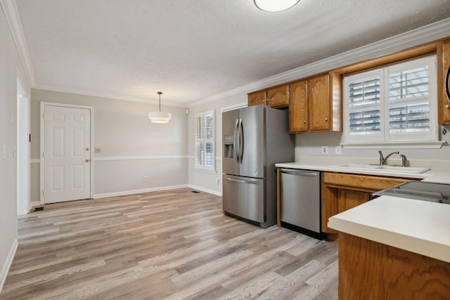 kitchen with decorative light fixtures, appliances with stainless steel finishes, sink, and ornamental molding