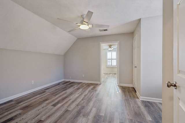 additional living space featuring a textured ceiling, ceiling fan, dark hardwood / wood-style flooring, and lofted ceiling