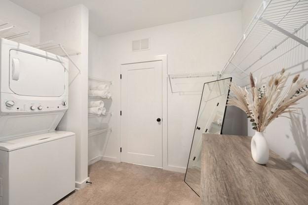 laundry room featuring light carpet and stacked washer and clothes dryer