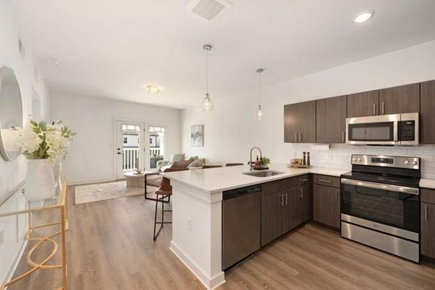 kitchen featuring pendant lighting, a kitchen bar, stainless steel appliances, sink, and kitchen peninsula