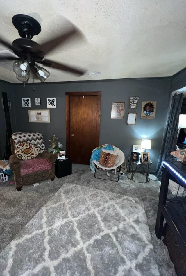 living area with ceiling fan, a textured ceiling, and carpet flooring