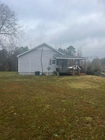 view of side of property featuring a lawn and a porch