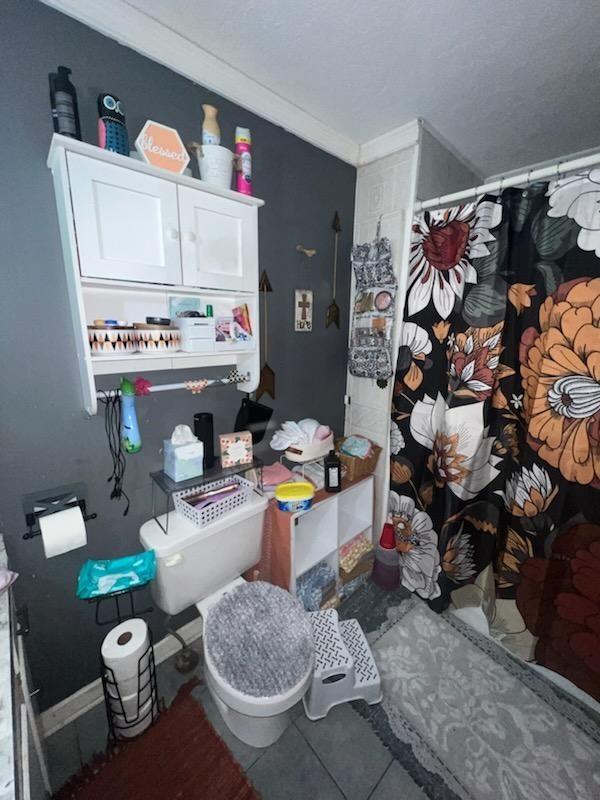 bathroom featuring toilet, tile patterned flooring, and ornamental molding