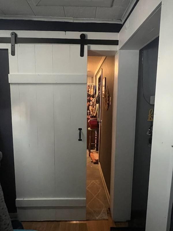 hallway featuring a barn door, crown molding, and hardwood / wood-style flooring