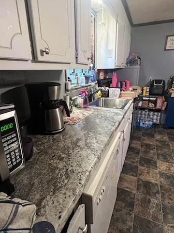 kitchen featuring white cabinets, light stone countertops, and sink