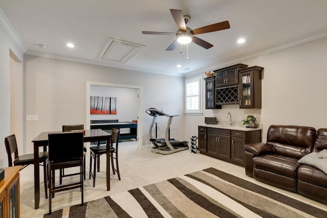 living room featuring wet bar, light colored carpet, ornamental molding, and ceiling fan