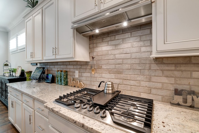 kitchen with white cabinetry, backsplash, stainless steel gas cooktop, ornamental molding, and light stone counters