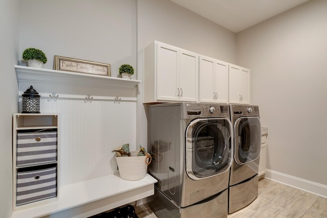 clothes washing area with washer and clothes dryer, light wood-type flooring, and cabinets