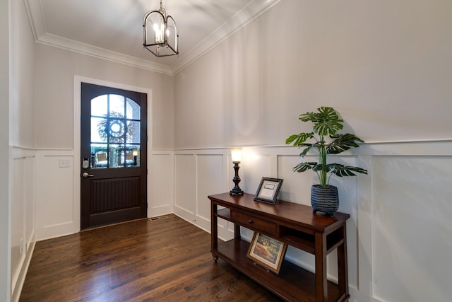 foyer entrance featuring dark wood-type flooring, crown molding, and a chandelier