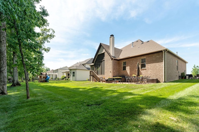 back of house with a playground and a yard