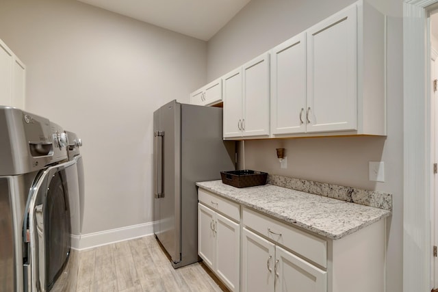 washroom with light wood-type flooring, independent washer and dryer, and cabinets