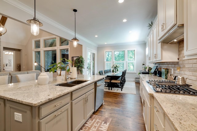 kitchen featuring light stone counters, pendant lighting, stainless steel appliances, and a kitchen island with sink