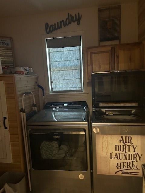 laundry room featuring separate washer and dryer and cabinets