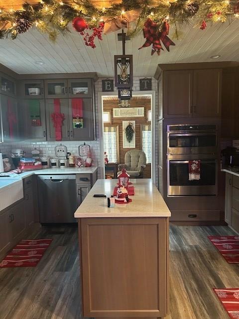 kitchen featuring appliances with stainless steel finishes, backsplash, dark hardwood / wood-style flooring, and a kitchen island