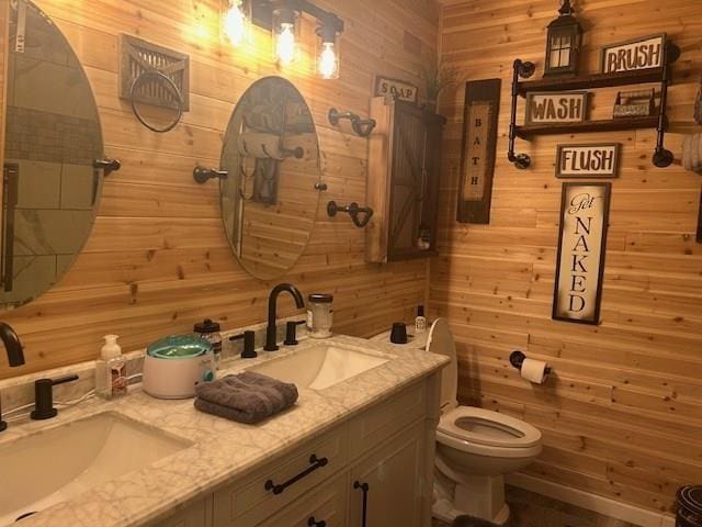 bathroom with toilet, vanity, and wooden walls