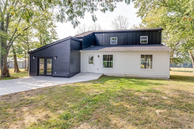 rear view of property featuring a lawn, french doors, and a patio