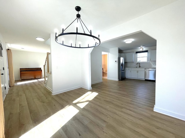 unfurnished dining area featuring light hardwood / wood-style floors, sink, and a notable chandelier