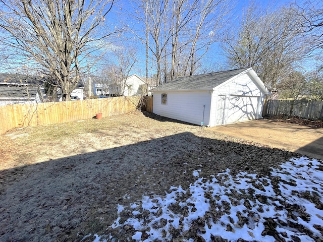 snowy yard with a garage and an outbuilding