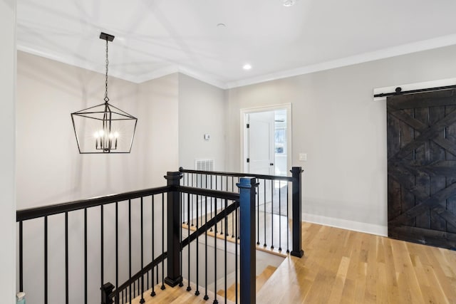 hallway featuring a barn door, crown molding, a chandelier, and hardwood / wood-style floors