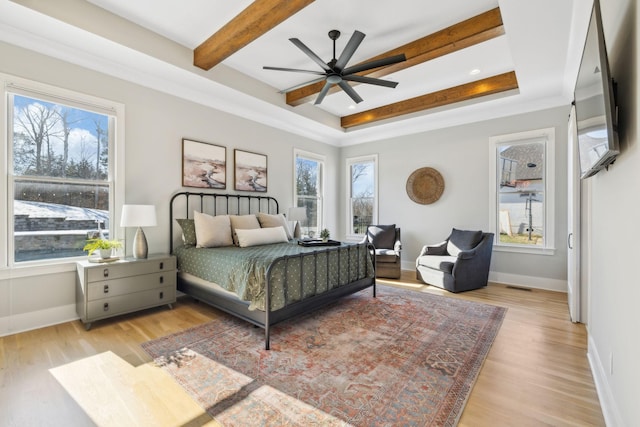 bedroom featuring ceiling fan, light hardwood / wood-style flooring, and a raised ceiling