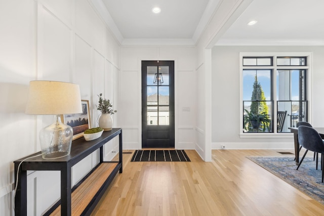 foyer featuring plenty of natural light, ornamental molding, and light hardwood / wood-style floors