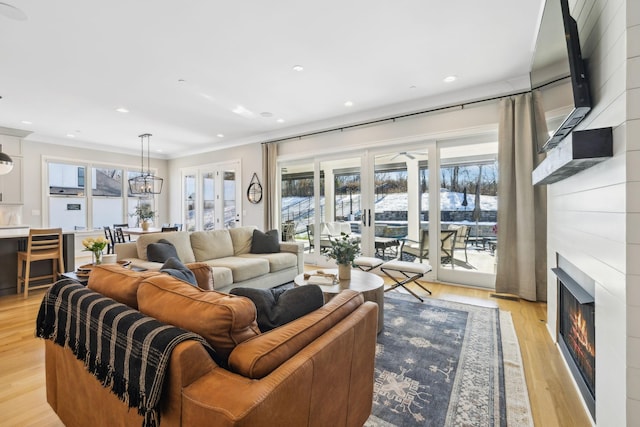 living room with light hardwood / wood-style floors, crown molding, and a notable chandelier