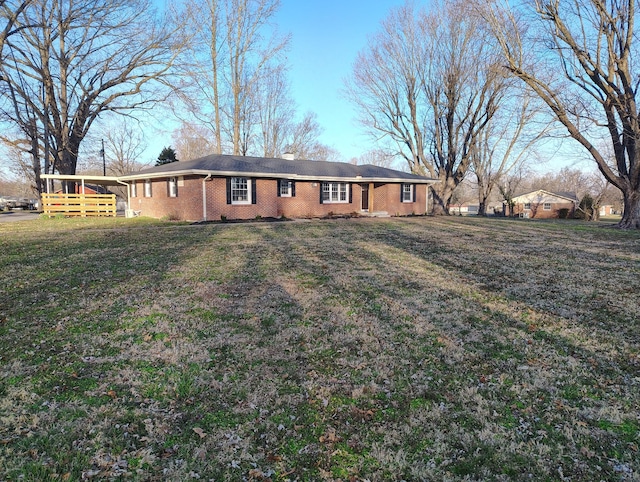 rear view of property with brick siding and a yard