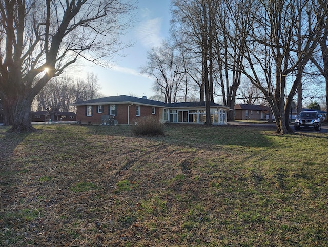 exterior space with brick siding and a front yard