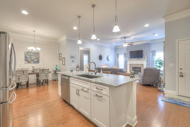 kitchen with appliances with stainless steel finishes, decorative light fixtures, white cabinetry, an island with sink, and sink