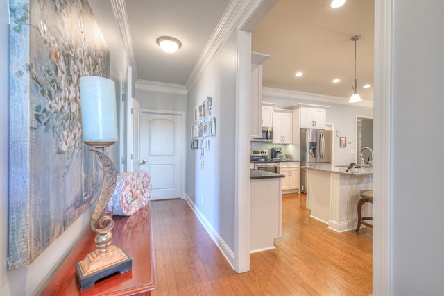 hallway featuring ornamental molding, light hardwood / wood-style floors, and sink