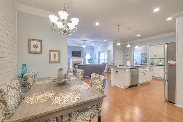 dining room featuring crown molding, sink, ceiling fan with notable chandelier, and light hardwood / wood-style floors